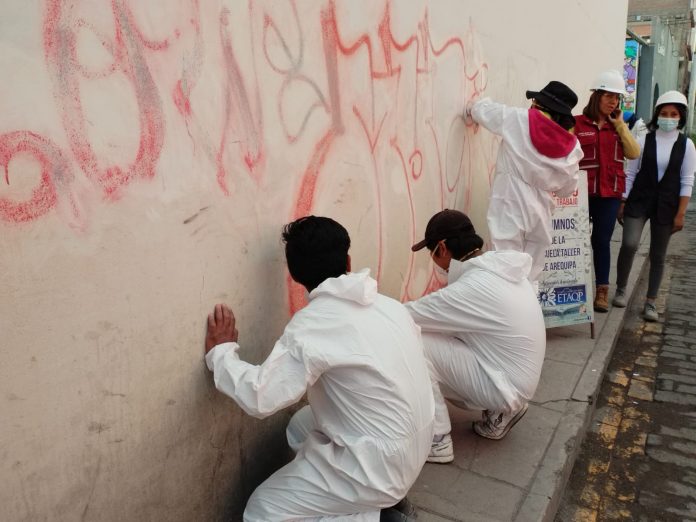 Voluntarios borran grafitis realizados en las calles del centro histórico por ciudadanos extranjeros